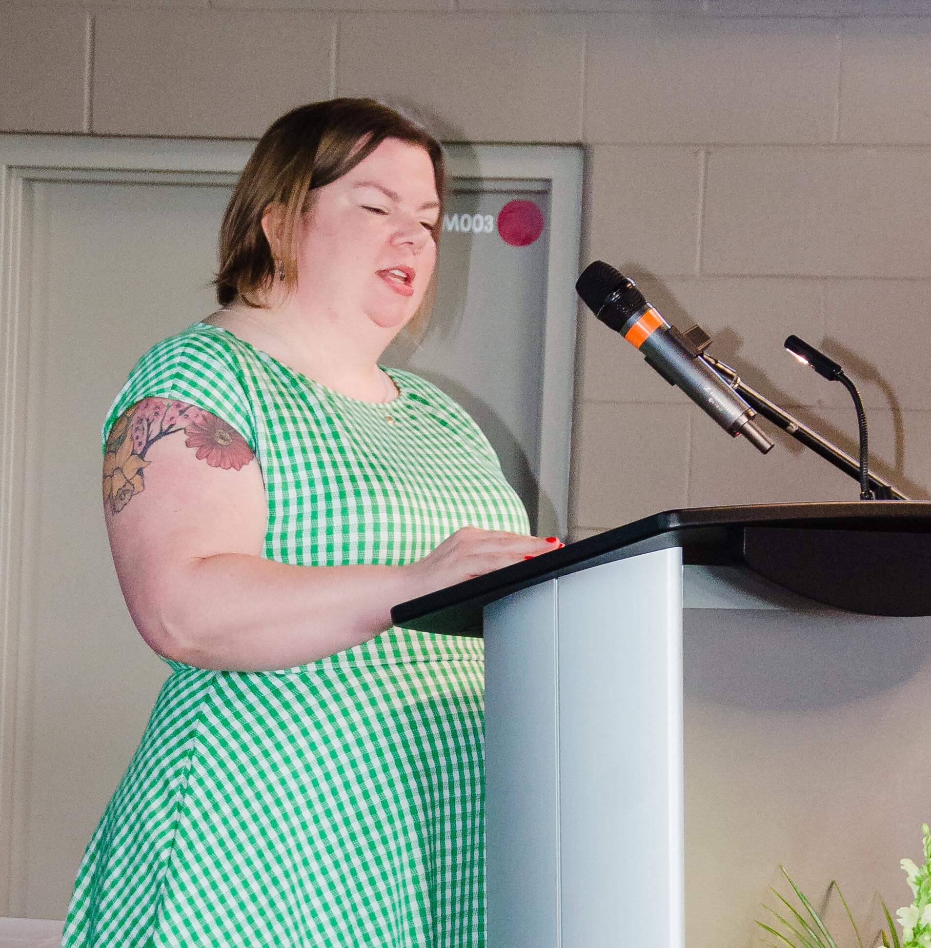 Laura Warkentine standing behind a podium with a microphone